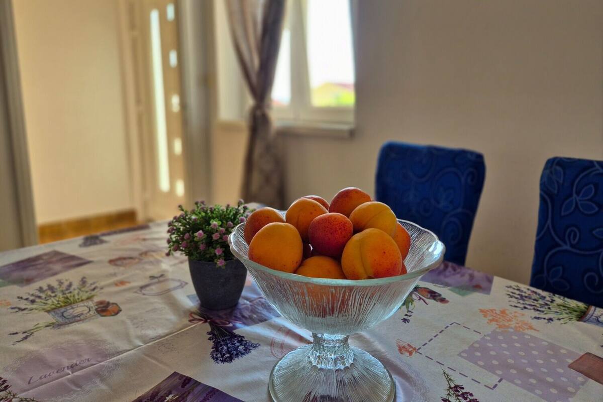 A glass bowl filled with peaches on a table with a floral tablecloth.