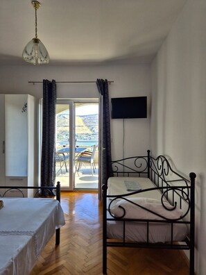 A bedroom with a bed, a TV, and a view of a terrace with outdoor furniture. - Apartments Josi (Sibenik)