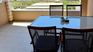 Ein Balkon mit Tisch und Stühlen, Blick auf einen See und eine Berglandschaft.