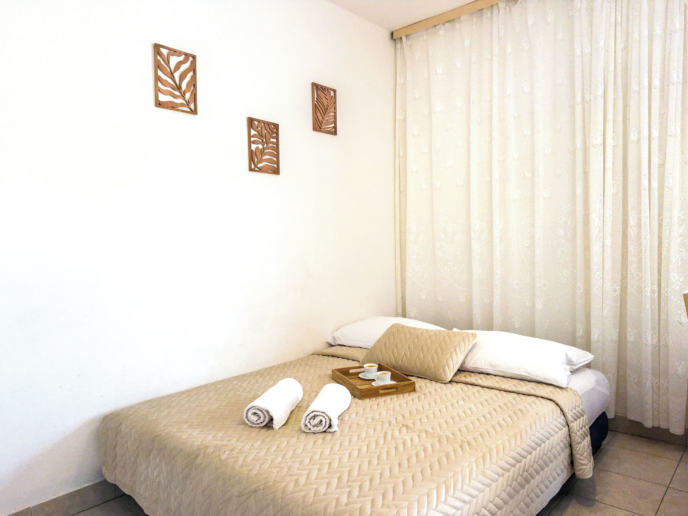 Una habitación de hotel con cama, ventana con cortinas y decoración en la pared.