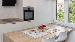 Une cuisine moderne avec des meubles blancs, un îlot central en bois et un four encastré.