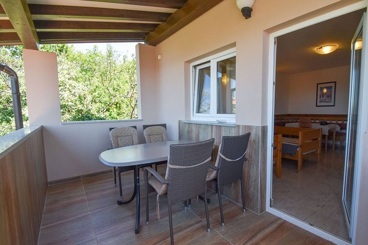 Une terrasse couverte avec une table et des chaises, une fenêtre et une vue sur l’extérieur.