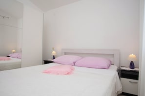 A bedroom with a bed, two nightstands, a mirror, and a dresser. - Apartments Ljubo (Vrsi)