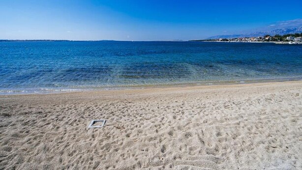 A beach with clear blue water and a sandy shore. - Apartments Ljubo (Vrsi)