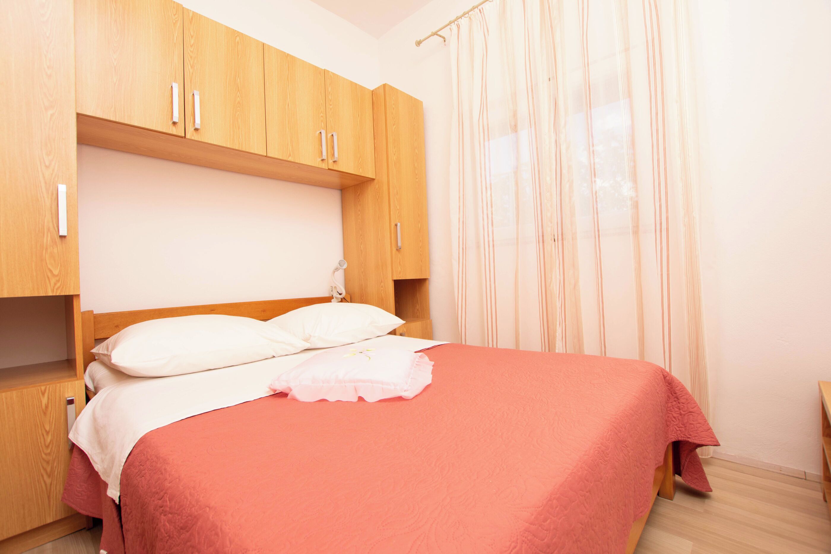 Une chambre à coucher avec un lit, une armoire en bois et une fenêtre avec des rideaux.