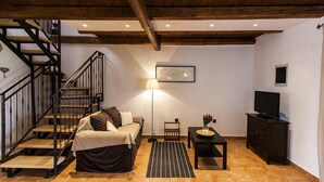 Una habitación acogedora con una cama, un escritorio, un televisor y una escalera.