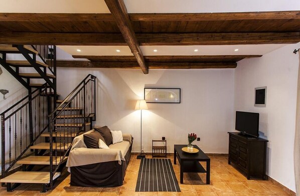 Um quarto aconchegante com uma cama, uma escrivaninha, uma televisão e um lance de escadas.