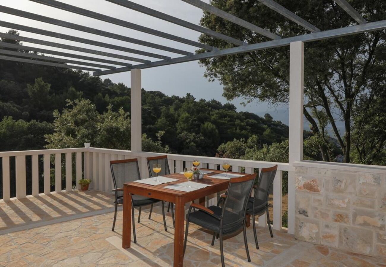 An outdoor patio with a stone floor, a wooden table with chairs, and a pergola structure.
