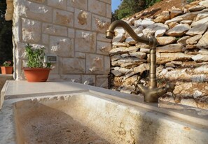 A stone wall with a built-in sink and faucet. - House Irena (Pucisca)