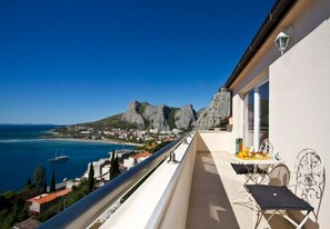 Un balcon avec une table et des chaises, donnant sur une ville côtière et la mer.