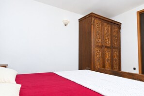 Een slaapkamer met een bed, een kledingkast en een wandlamp.