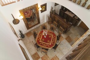 A dining area with a round table, chairs, a chandelier, a mirror, and a cabinet with decorative items. - House Villa Oaza (Rogoznica)