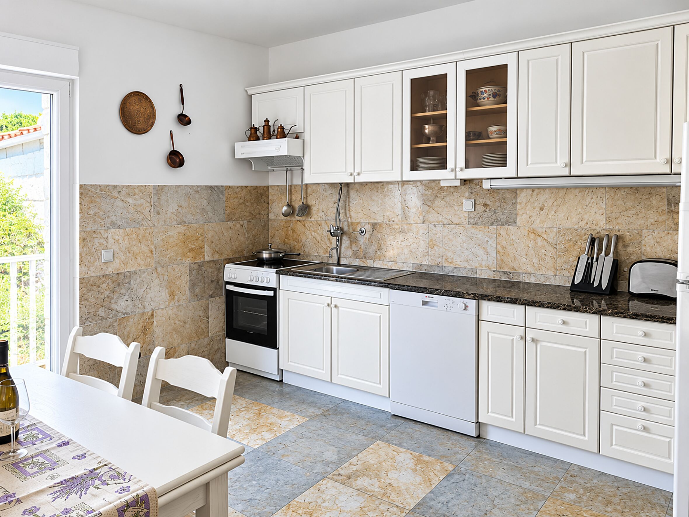 A modern kitchen with white cabinetry, a granite countertop, and a dining area with a table and chairs.