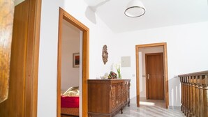 A hallway with wooden doors, a marble floor, and a wooden railing on the right. - House Villa Oaza (Rogoznica)