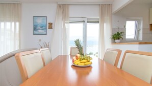 A dining area with a wooden table, a fruit bowl, and a view of the outdoors. - Apartment The View (Trogir)