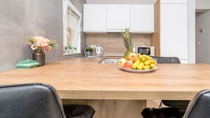 A modern kitchen with white cabinets, a wooden countertop, and a fruit bowl. - Apartment The View (Trogir)
