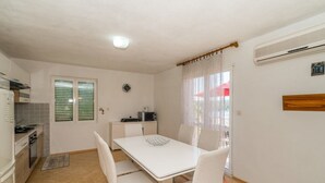 A compact kitchen with a dining table, chairs, a microwave, and a small refrigerator. - Apartment Ivan (Solta)