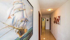 A hallway with a large maritime painting, a door leading to a bathroom, and a small round mirror on the wall. - Apartment Ivan (Solta)