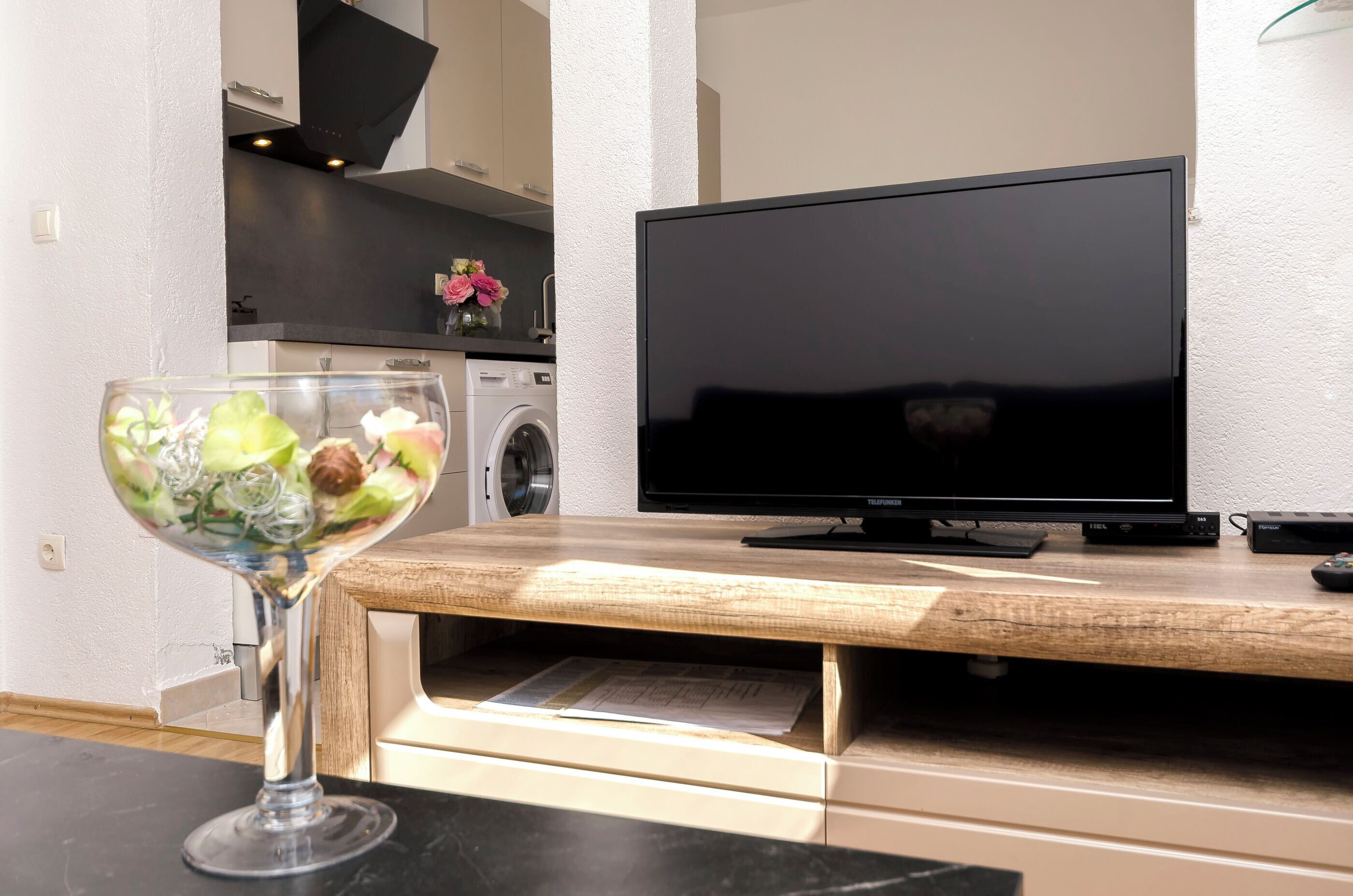 Una cocina moderna con televisor de pantalla plana, lavadora y encimera de madera.