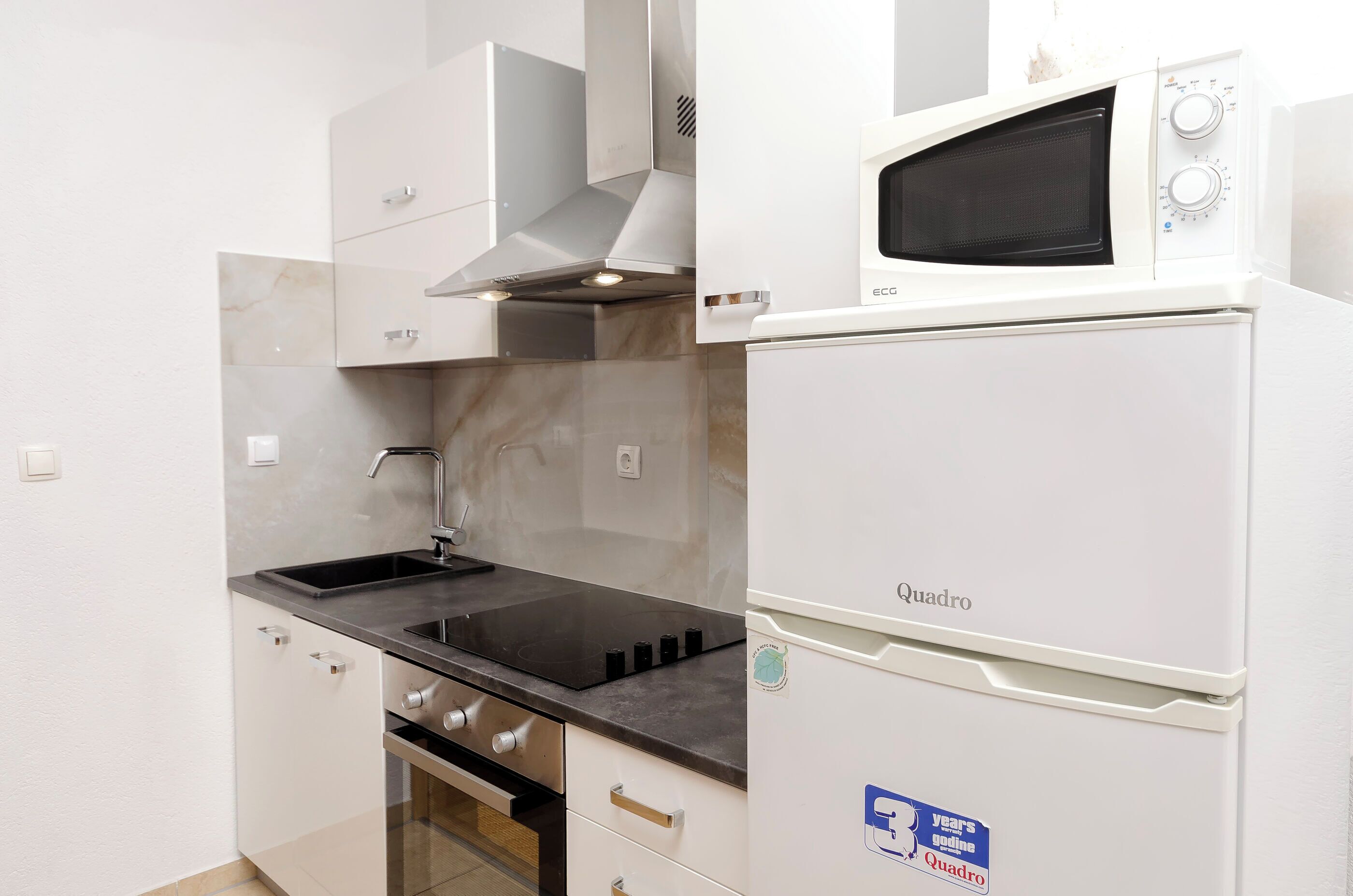 A compact kitchen with a built-in microwave, stove, and sink.