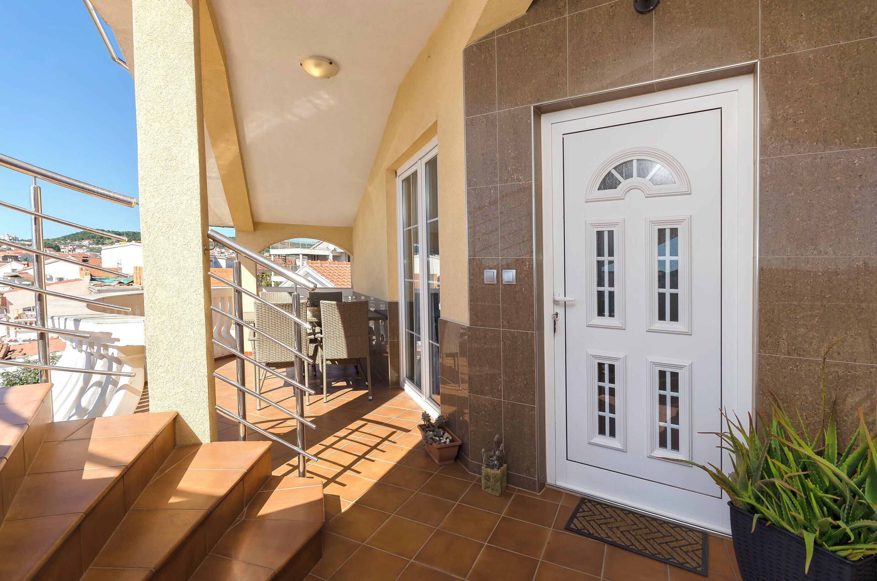 Entrada de hotel com porta branca, escadaria e vista dos edifícios ao redor.