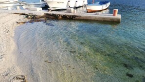 Una marina con imbarcazioni ormeggiate, acqua cristallina e una spiaggia sabbiosa.