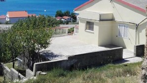 Un edificio costero con techo rojo, un pequeño porche y vistas al mar.