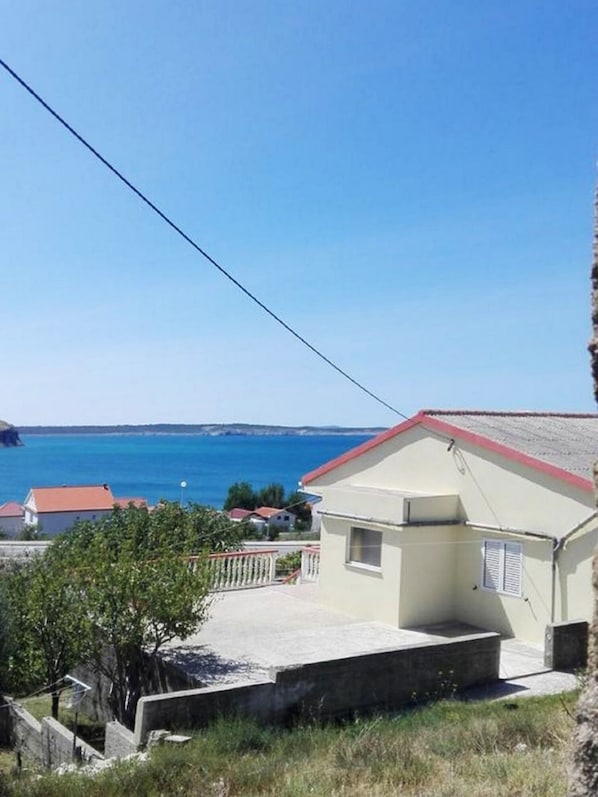 A coastal building with a red roof, a small porch, and a view of the sea. - Apartment Jopek (Razanac)