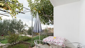 Un patio con mesa y sillas, una sombrilla colgante y vistas al jardín.