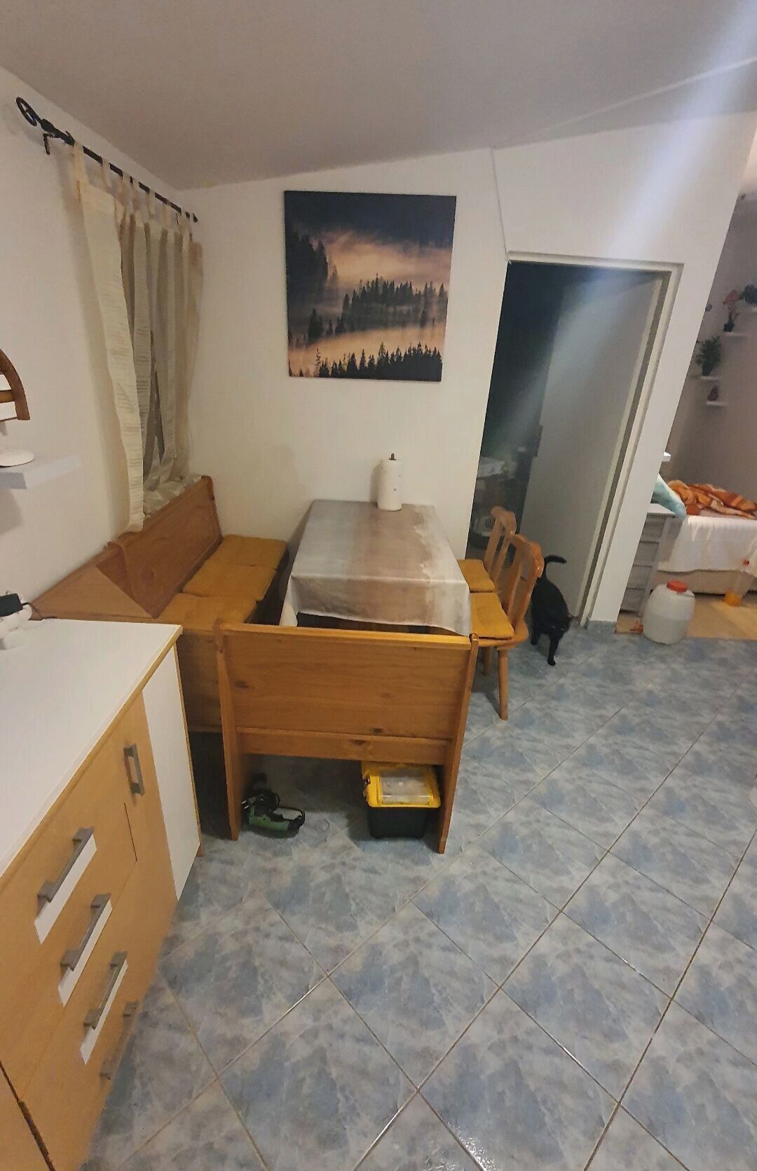 Un espace de vie compact comprenant un canapé, une petite table à manger, un meuble et un sol carrelé.