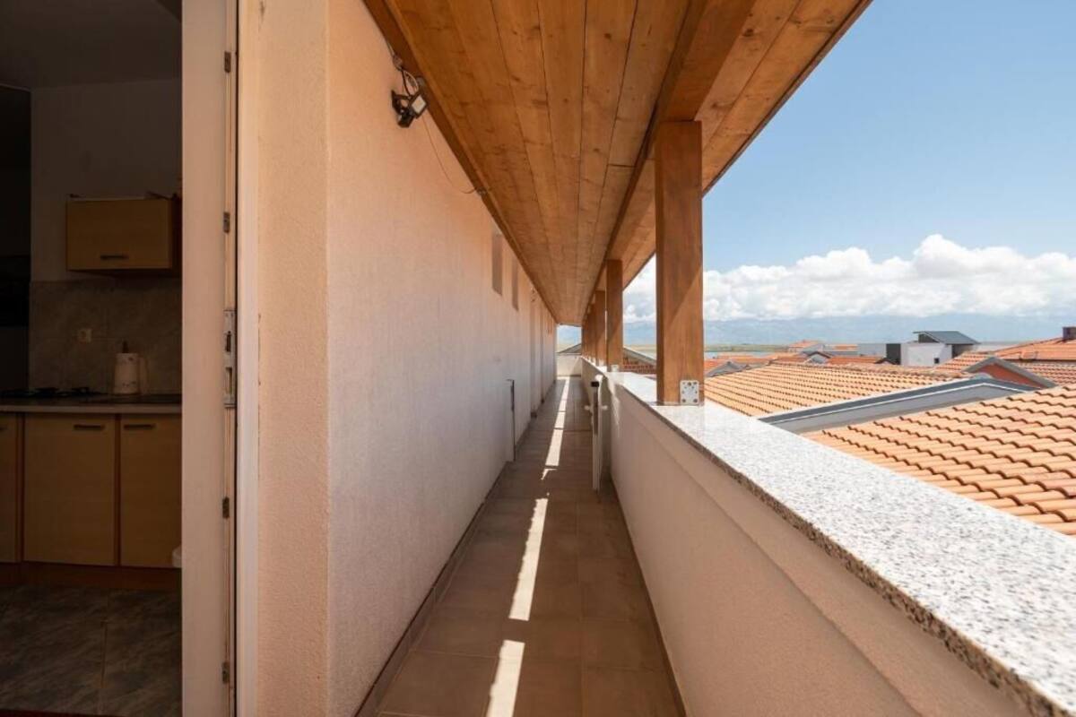 Un pasillo estrecho con techo de madera y vistas a tejados de tejas rojas.
