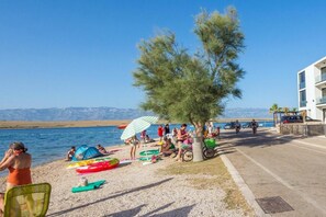 Eine Strandansicht mit Menschen, die entspannen, einem Zelt und einem Baum.