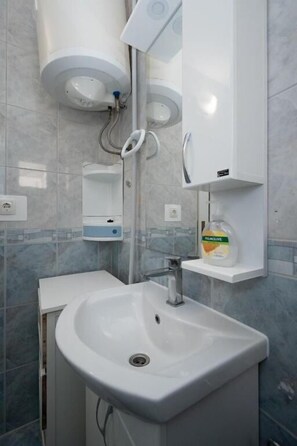 A bathroom with a white sink, a mirror, a soap dispenser, and a towel rack. - Apartments Gavro (Vir)