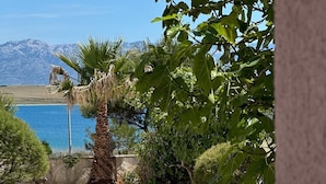A stone-paved patio with a view of a body of water and mountains in the background. - Apartment Island of Love (Vir)