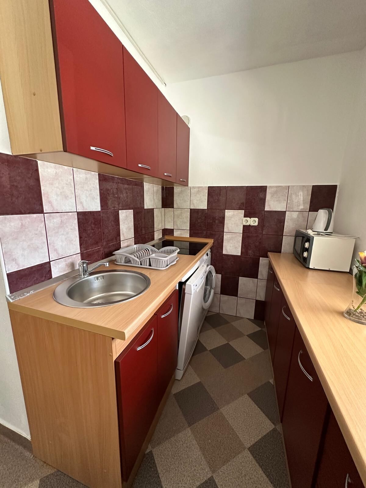A compact kitchen with a sink, washing machine, and a toaster.