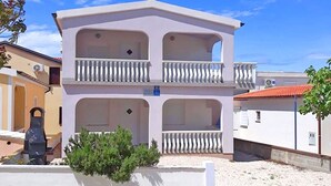 A two-story building with balconies, a small garden area, and a clear sky. - Apartment Island of Love (Vir)