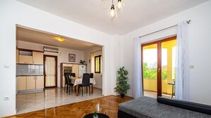 A modern living room with a sofa, a dining table, and a kitchen in the background. - Apartment Mari (Novigrad)