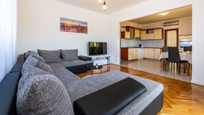 A modern living room with a large sectional sofa, a flat-screen TV, and a dining area with a table and chairs. - Apartment Mari (Novigrad)