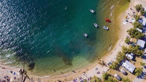An aerial view of a beach with clear waters, boats, and a row of cabins. - Apartment Mari (Novigrad)