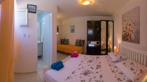 Un dormitorio con una cama, un armario, un espejo y un cuadro en la pared.