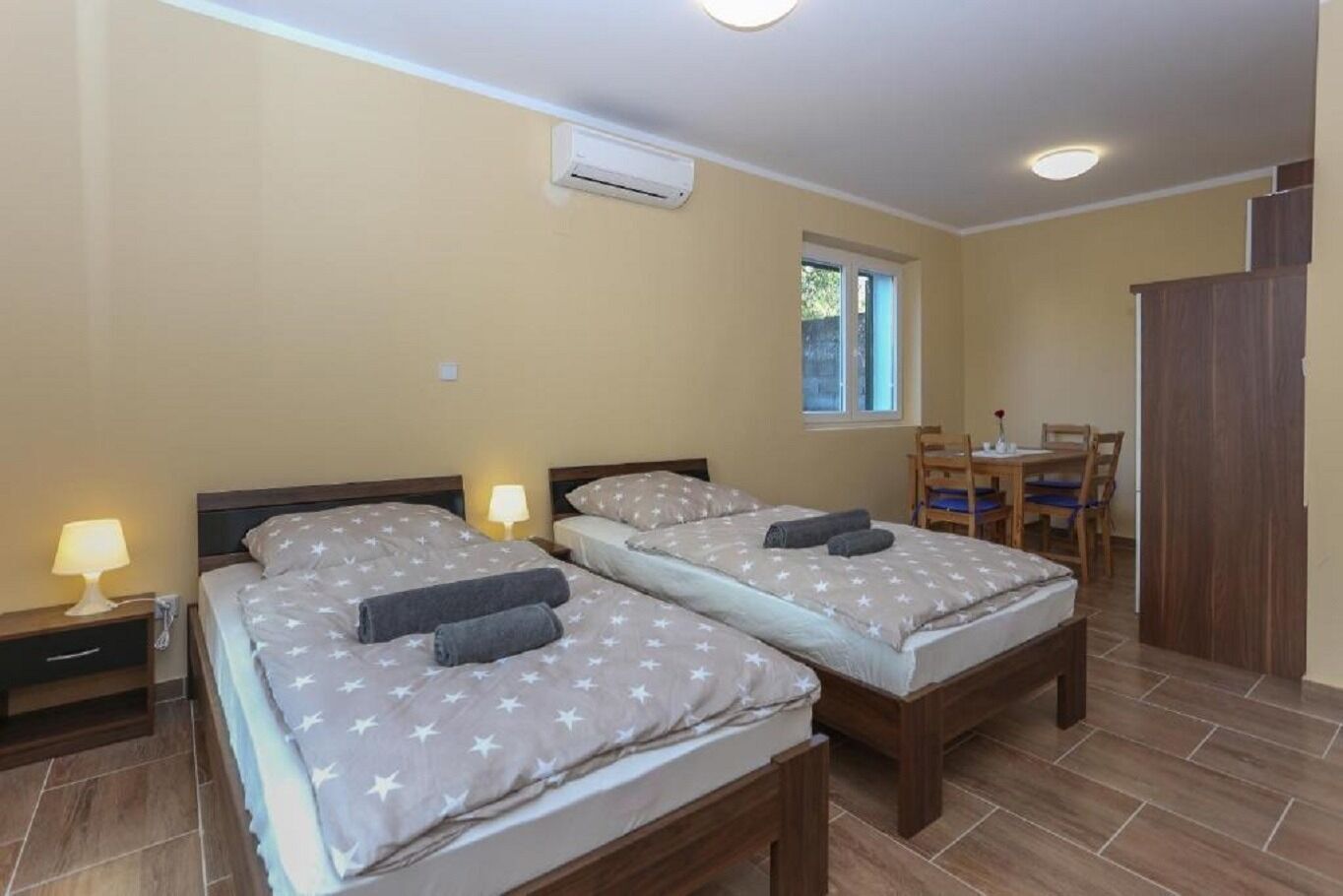 A room with two beds, a small table, and a window.