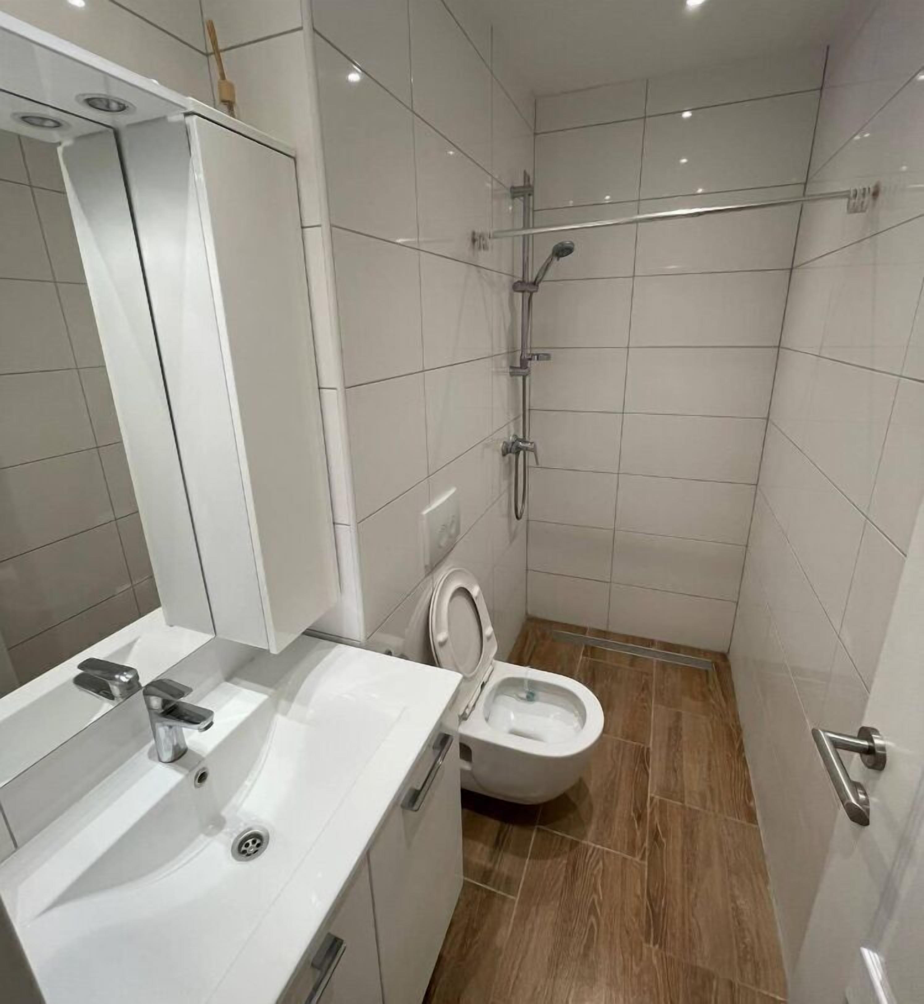 Un baño moderno con lavamanos, espejo y retrete blancos.