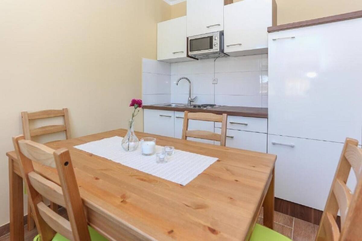 Een kleine keuken met witte kastjes, een magnetron en een spoelbak.
