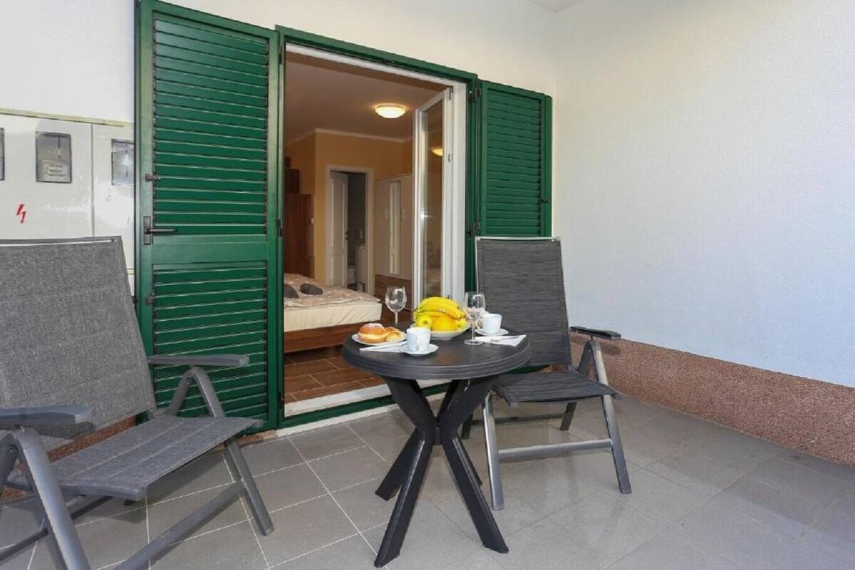 Een klein balkon met een ontbijttafel, compleet met brood, bananen en wijnglazen.