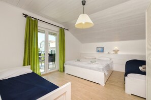 A bedroom with a bed, a chair, a table, and a window with curtains. - Apartment Denko by the sea (Tisno)