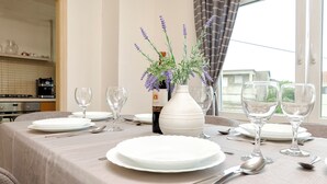 A dining table set with white plates, silverware, and wine glasses, with a vase of lavender flowers in the center. - Apartment Denko by the sea (Tisno)