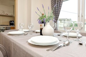 A dining table set with white plates, silverware, and wine glasses, with a vase of lavender flowers in the center. - Apartment Denko by the sea (Tisno)