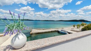 A coastal view with a white vase of purple flowers, clear blue sky, and calm sea. - Apartment Denko by the sea (Tisno)