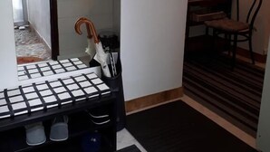 A small, narrow hallway with a tiled floor, a black mat at the entrance, a chair, and a table with a black and white checkered tablecloth. - Apartment Milan (Zagreb)