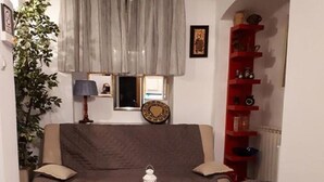 A living room with a sofa, a small round table, a red bookshelf, and a patterned rug. - Apartment Milan (Zagreb)